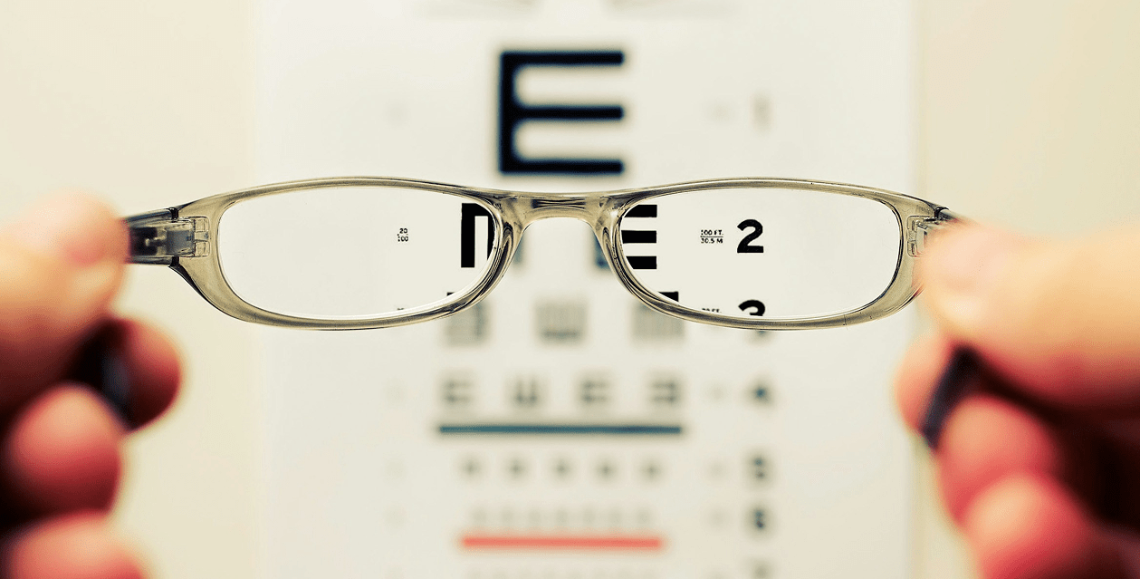 Glasses being held up to an eye test graph
